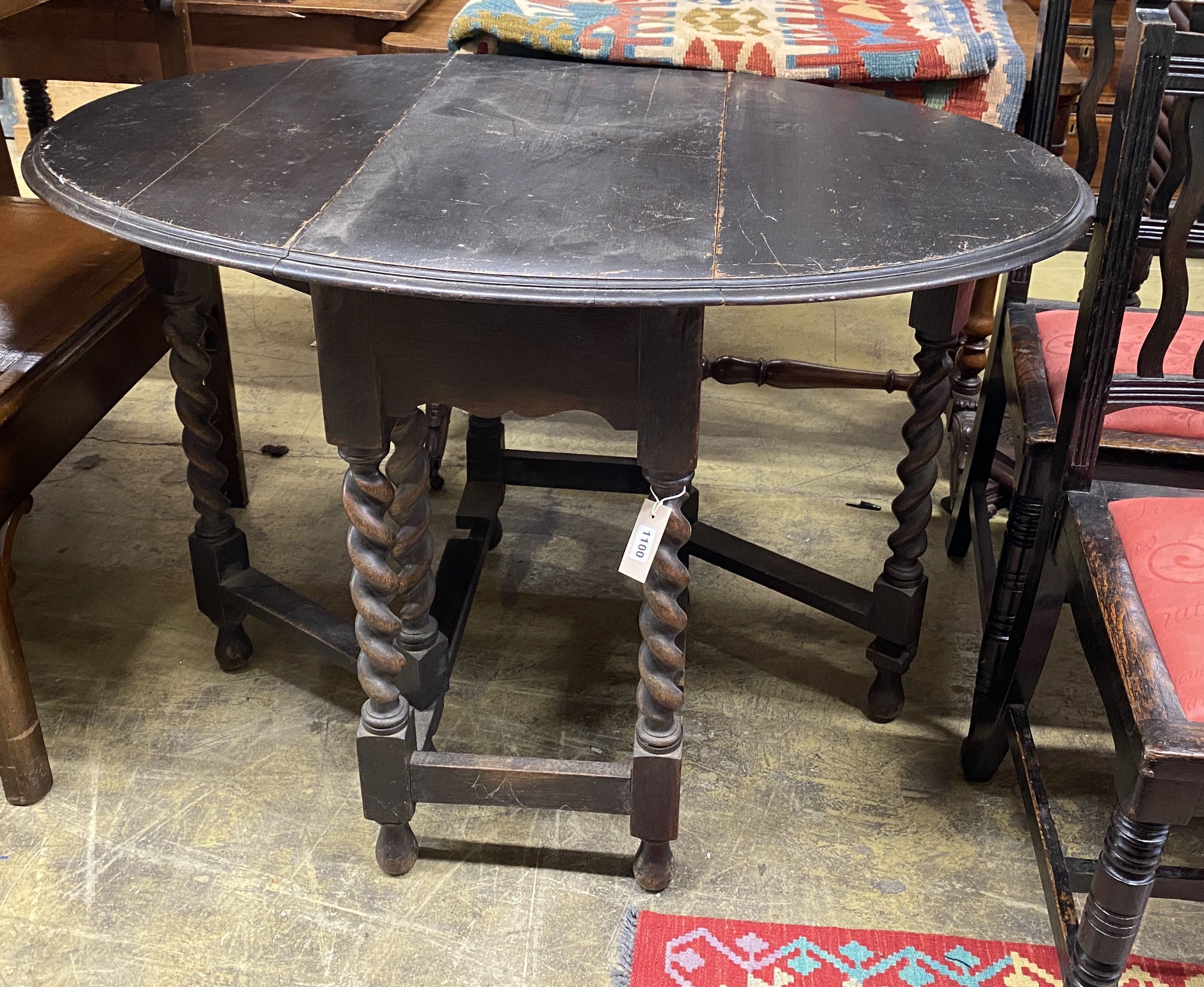 An early 20th century oak oval gateleg table, 106cm extended, width 74cm, height 74cm together with two oak dining chairs